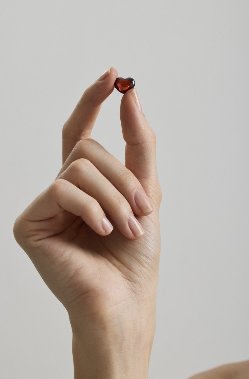 A garnet heart held between two fingers